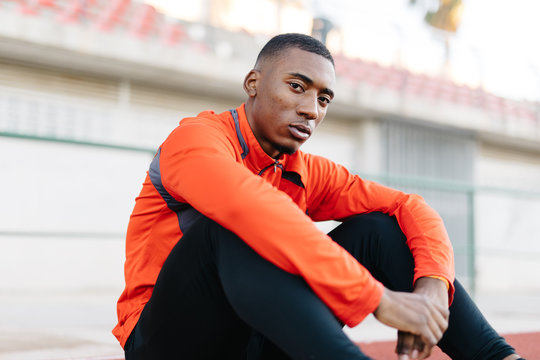 Black sportsman sitting on running track