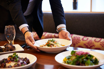 Waiter Placing Food On Table At Restaurant