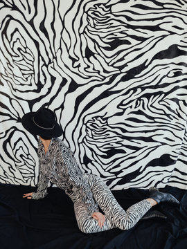 Anonymous stylish female looking at zebra wall