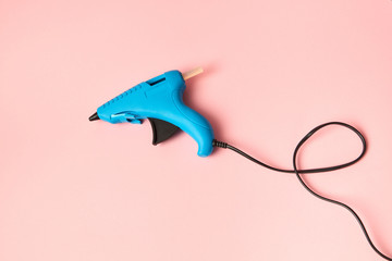 New blue glue gun for handcraft working on a color of the year 2019 Living Coral pantone background, copy space.