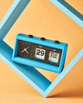 Blue flip clock on square shelf, retro analog timer show date 29, day tuesday on an yellow background, copy space.