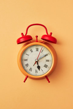 Retro style yellow alarm clock with red bells on an yellow backg