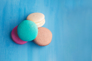 Sweet and bright colourful macarons on blue background. French dessert.