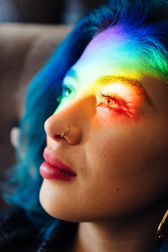 Close up of young woman with rainbow lights on her face