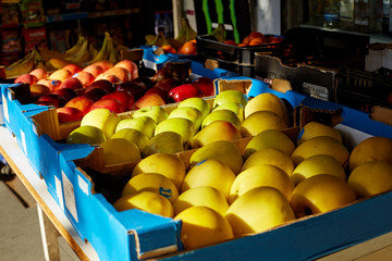 Apples yellow, green, red lie in blue cardboard boxes lie on the counter in the store