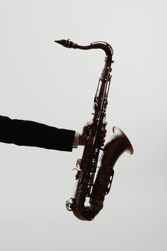 Hand holding saxophone with white background