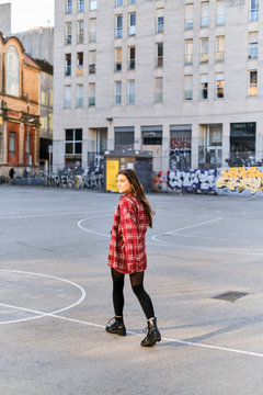 beautiful, cheeky girl in a plaid shirt, posing in the sun against the background of a painted wall