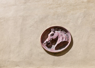 Fototapeta na wymiar Horse head carved from stone on the wall. Tuscamny, Italy.