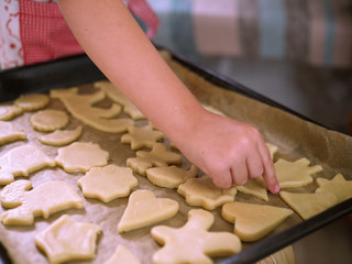 a child at home cuts out cookie cutters.