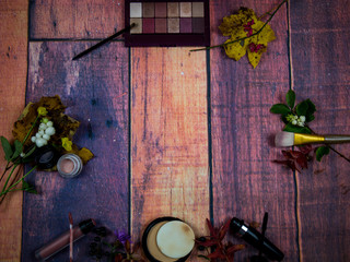 Various makeup products on wooden background with autumn decoration