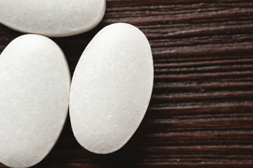 White medical supplement pills on wooden background, macro image, top view