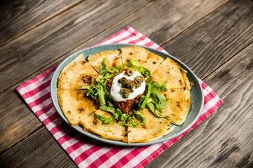 tortilla with tomato sauce, olives and sour cream