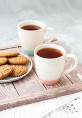 A tasty snack: two cups of tea and a plate of cookies..