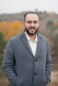 portrait of a laughing man in a coat on the background of nature