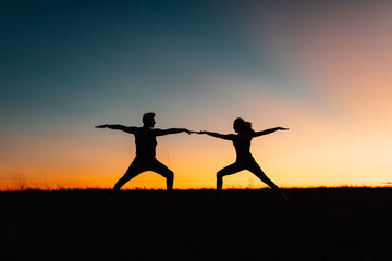 Silhouettes of people training yoga