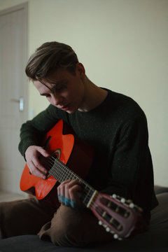portrait of a handsome guy with a guitar on the couch
