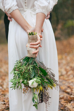 photo of the bride's bouquet in her hands against the background of a white dress