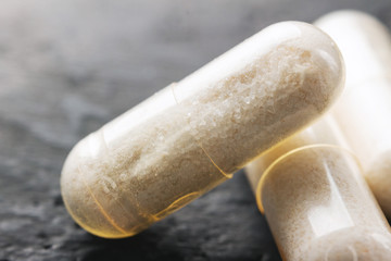 White medical capsules of glucosamine chondroitin, healthy supplement pills on dark background,...