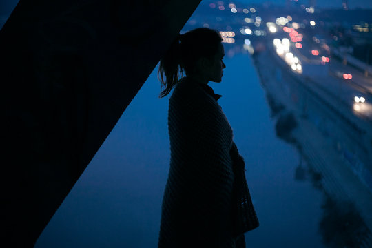 silhouette of a girl on the background of the night city and the road