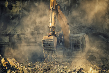 Heavy machinery surrounded with dust  cloud taking down an old building  - obrazy, fototapety, plakaty