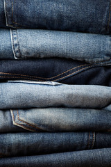 Stack of various blue jeans on black background. Beauty and fashion, clothing concept. Detail of nice blue jeans. Jeans texture or denim background. Collection of jeans. the blue jeans fabric details