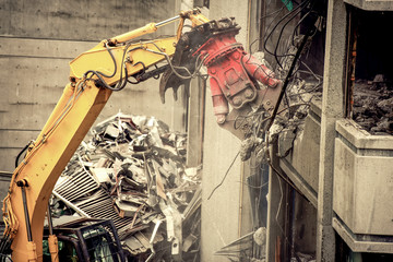 Heavy machinery surrounded with dust  cloud taking down an old building 
