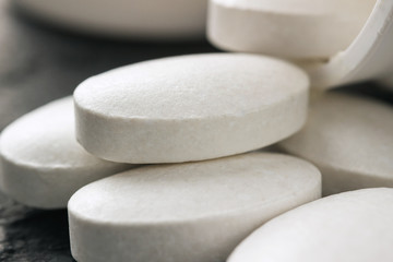 Fototapeta na wymiar White medical supplement pills on dark background, macro image