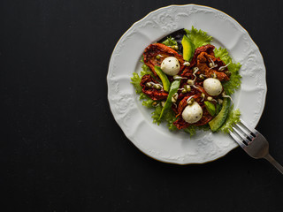 salad made from dried tomatoes, pe-tsai, avocado, and mozzarella cheese. close-up.