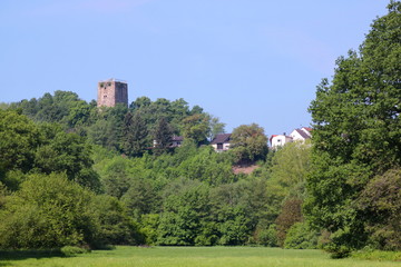 Fototapeta na wymiar The medieval castle and the village of Burgsponheim towering over a beautiful green valley forest in Germany