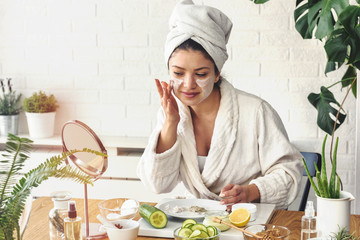 Young woman applying face mask at home. Natural Skin Care Routine. Cleaning face with natural...