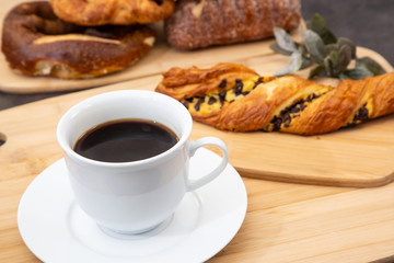 Breakfast with croissants, leaves, cutting board and black coffee on the morning breakfast.
