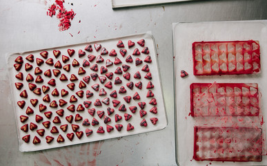 Finished heart shaped chocolates next to their moulds.