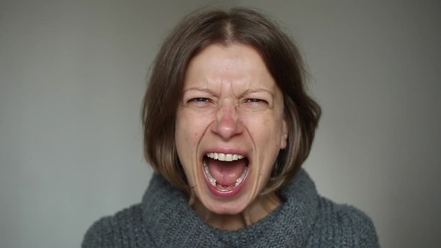 An angry woman shouts aggressively at the camera.