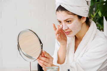 Young woman applying face mask at home. Natural Skin Care Routine. Cleaning face with natural...