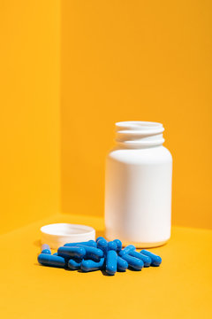 Blue Pills And Bottle On A Yellow Background