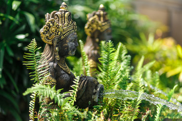 Balinese statuette of a girl with a pot from which water flows. Pool decoration