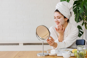 Young woman applying face mask at home. Natural Skin Care Routine. Cleaning face with natural...