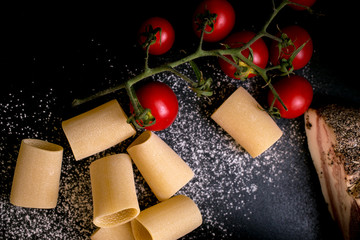 Fototapeta premium Paccheri pasta, Guanciale and cherry tomatoes on black background