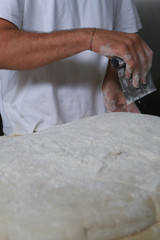 Bakers making handmade loaves of bread in a family bakery shaping the dough into tradional shapes. Working hands kneading bread dough