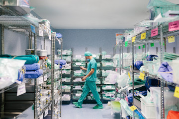 Nurse walking in the warehouse while using a smartphone