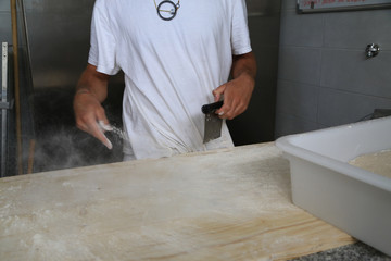 Bakers making handmade loaves of bread in a family bakery shaping the dough into tradional shapes. Working hands kneading bread dough