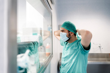 Unrecognizable doctor covering his face with mask