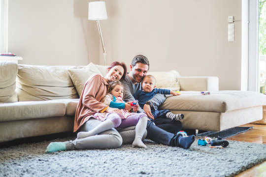 Portrait of happy parents sitting with children in living room at home