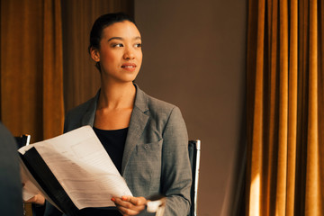 Thoughtful female lawyer with document looking away at law office