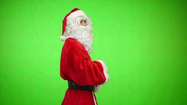 Santa Claus turn around from back and welcomes. green background