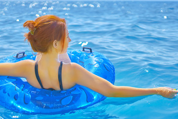 Beautiful young woman relax on blue inflatable ring in sea water