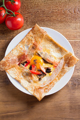 Healthy vegetarian homemade food: crepes or thin pancakes with cheese, egg, tomatoes and mushrooms. Overhead vertical image