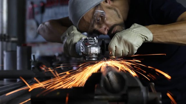 Man work with angle grinder, goggles and construction gloves, grinder metal in garage workshop, do it youself concept, sparks close up