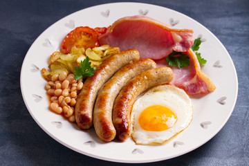 Full English or Irish breakfast with sausages, bacon, egg, tomatoes, fries and beans. Nutritious and healthy morning meal