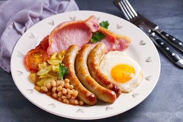 Full English or Irish breakfast with sausages, bacon, egg, tomatoes, fries and beans. Nutritious and healthy morning meal